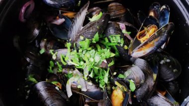 Çoklu buharlı midyeleri üzerinde maydanoz olan bir tencereye koy.