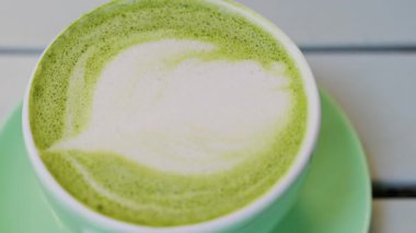 Teras masasındaki yeşil bardakta bir kibrit sütlü latteyi kapat.