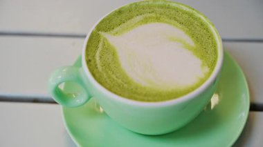 Teras masasındaki yeşil bardakta bir kibrit sütlü latteyi kapat.