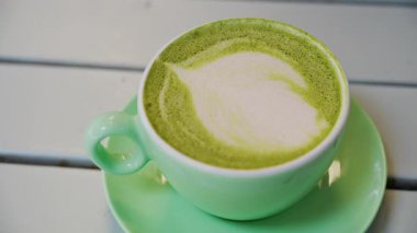 Teras masasındaki yeşil bardakta bir kibrit sütlü latteyi kapat.