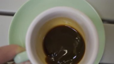 Yeşil bir tabakta bir fincan espresso çeviren bir adamın elini kapat.