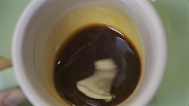 Yeşil bir tabakta bir fincan espresso çeviren bir adamın elini kapat.