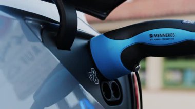 Antibes, Fransa - 25 Mayıs 2025: Beyaz bir arabaya takılı mavi bir elektrikli araba şarjı