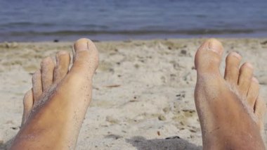 Deniz manzaralı kumlu sahilde bir adamın ıslak ve kumlu ayaklarına yaklaş.