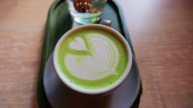 Matcha latte ve bir bardak suyu bir kafedeki küçük yeşil tepside kapatıyoruz.