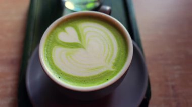 Matcha latte ve bir bardak suyu bir kafedeki küçük yeşil tepside kapatıyoruz.