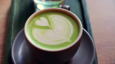 Matcha latte ve bir bardak suyu bir kafedeki küçük yeşil tepside kapatıyoruz.