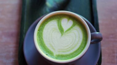 Matcha latte ve bir bardak suyu bir kafedeki küçük yeşil tepside kapatıyoruz.