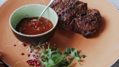 Yanında barbekü sosu ve mikro bitkiler olan sığır filetosu bifteğini kapat.