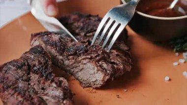 Yanında barbekü sosu ve mikro bitkilerle sığır filetosu kesen bir kadının ellerini kapatın.