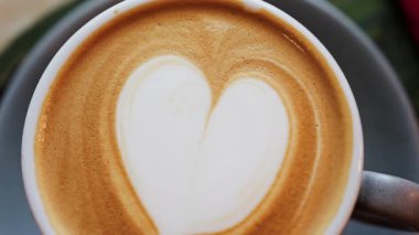 Siyah bardakta bir latte ile yapılmış bir kalbi kapat.