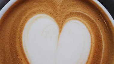 Siyah bardakta bir latte ile yapılmış bir kalbi kapat.