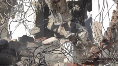 Gündüz vakti hidrolik kırıcıyla beton binayı yıkan bir kazıcı.