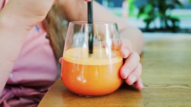 Bir kadının bir bardak portakal suyuna siyah bir pipetle karışması.