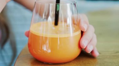 Bir kadının bir bardak portakal suyuna siyah bir pipetle karışması.