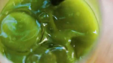 Bir bardak buzlu portakal suyuna karıştırılmış bir elin yakın çekimi. Kafedeki bir masada siyah bir pipetle eşleşiyor.