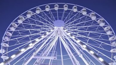 Beyaz, aydınlık dönme dolap manzarası Antibes, Fransa 'da gökyüzü ile birlikte dönüyor.