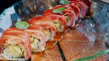 Bir restoranda cam tepsiye serpiştirilmiş soslu suşiyi kapat.