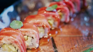 Bir restoranda cam tepsiye serpiştirilmiş soslu suşiyi kapat.