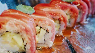 Bir restoranda cam tepsiye serpiştirilmiş soslu suşiyi kapat.