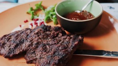 Yanında barbekü sosu ve mikro bitkiler olan sığır filetosu bifteğini kapat.