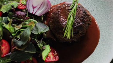 Kırmızı şarap soslu fileminyon ve taze salata garnitürlü.