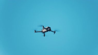 Mavi gökyüzüne karşı uçan bir dronun alçak açılı görüntüsü