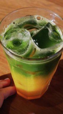 Kafedeki bir masada bir bardak buzlu portakal suyu eşleşmesi. Dikey