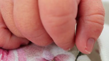 Yeni doğmuş bir bebeğin, dinlenirken yumuşak doğal ışığa sarılmış minik elini kapat.