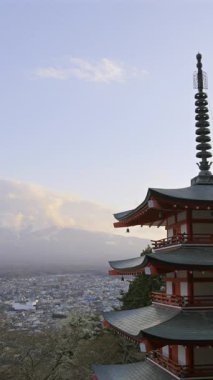 Fujiyoshida 'ya tepeden bakan Chureito Pagoda' nın güzelliğini keşfedin. Büyüleyici günbatımı renkleri ve şehrin panoramik manzarası.