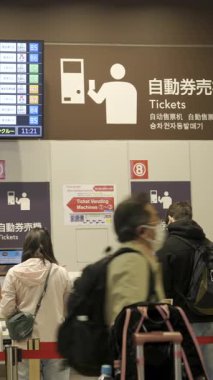 Tokyo, Japonya - 8 Nisan 2025: Bir Shinjuku otobüs durağında, bireyler bilet gişelerinde sıraya dizilmiştir. Otobüs saatlerini gösteren işaretler.