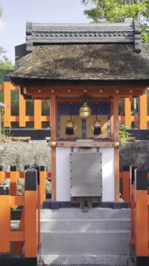 Kyoto, Japonya - 10 Nisan 2025: Fushimi-inari türbesi turuncu çitlerin bulunduğu ağaçların arasına yerleştirildi. Japon kültürüne özgü sakin atmosferi ve geleneksel mimariyi tecrübe edin..