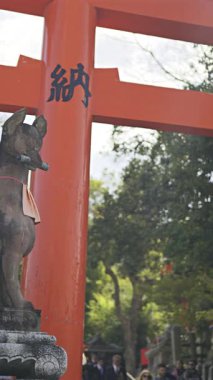 Kyoto, Japonya - 9 Nisan 2025: Renkli kırmızı kemer yolu, tarihi binalarla çevrili ünlü Fushimi Inari türbesini karşılıyor.
