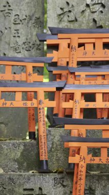 Kyoto, Japonya - 9 Nisan 2025: Her biri geleneksel karakterlerle işlenmiş küçük kırmızı torii kapıları. Sahne Japon kültürünün ve maneviyatının güzelliğini yakalıyor. Fushimi Inari