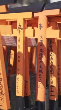 Kyoto, Japonya - 9 Nisan 2025: Her biri sembolik dini karakterlerle işlenmiş kırmızı torii kapılarıyla süslenmiş huzurlu bir tapınak keşfet.