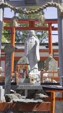 Kyoto, Japonya - 9 Nisan 2025: Ziyaretçiler Japonya 'da kırmızı torii kapıları ve karmaşık heykellerle süslenmiş huzurlu bir tapınağa hayran kaldılar.