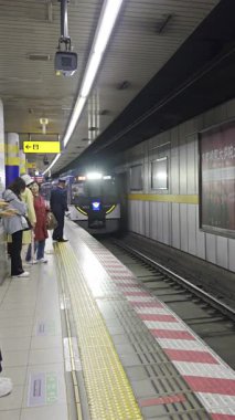Kyoto, Japonya - 10 Nisan 2025: İnsanlar metro istasyonunun peronunda maske takmış trenlerini beklerken.