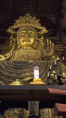 Nara, Japonya - 10 Nisan 2025: Todai-ji Budist tapınağındaki dingin altın Buda heykeli hafifçe aydınlatıldı. Büyük Buda Salonunun içi