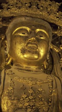 Nara, Japonya - 10 Nisan 2025: Todai-ji Budist tapınağındaki dingin altın Buda heykeli hafifçe aydınlatıldı. Büyük Buda Salonunun içi