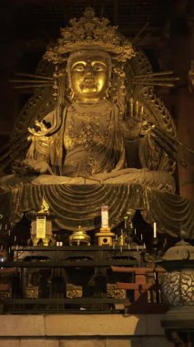 Nara, Japonya - 10 Nisan 2025: Todai-ji Budist tapınağındaki dingin altın Buda heykeli hafifçe aydınlatıldı. Büyük Buda Salonunun içi