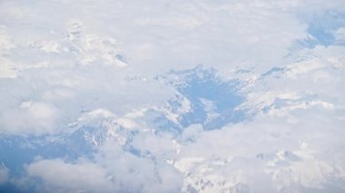 Bir uçak penceresinden beyaz, kabarık bulutların havadan görünüşü