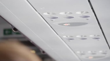 Uçak koltuklarının üstündeki paneller ve sigara içilmez tabelası.