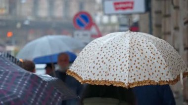 Milano, İtalya 'da elinde şemsiye tutan insanlar yağmurda yürüyor.
