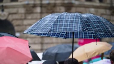 Milano, İtalya 'da elinde şemsiye tutan insanlar yağmurda yürüyor.