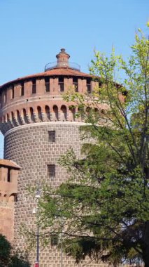 Milano, İtalya 'daki Sforzesco Kalesi' nin mavi arka planda yeşil ağaçlarla çevrili görüntüsü. Dikey