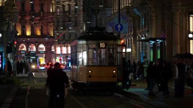 Milan, İtalya - 22 Mart 2025: İnsanlar gece tramvaya binip iniyorlar