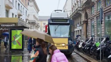 Milan, İtalya - 23 Mart 2025: İnsanlar yağmurlu bir günde sarı tramvaya biniyor