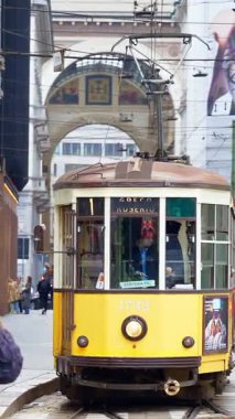 Milan, İtalya - 21 Mart 2025: Sarı tramvay gün ışığında şehrin sokaklarında hareket ediyor. Dikey