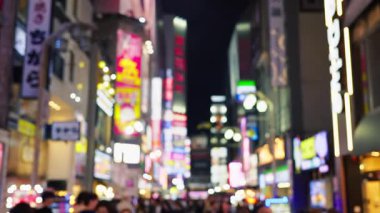 Shinjuku şehrinin hayat dolu manzarası bulanık. İnsanlar akşamları yanan binalarla sokaklarda dolaşıyorlar.