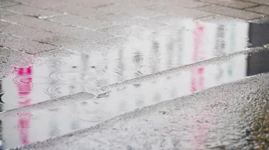 Gün ışığında yağmur damlaları şehir sokaklarında su birikintileri oluşturuyor. Tokyo, Japonya